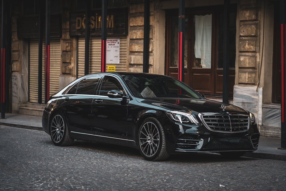 Sleek black luxury sedan parked on a cobblestone street in a historic European city