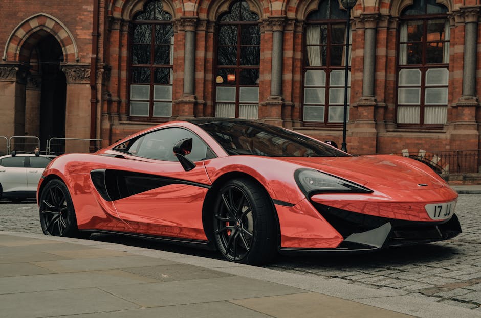 A sleek red sports car parked on a cobblestone city street in front of a historic building