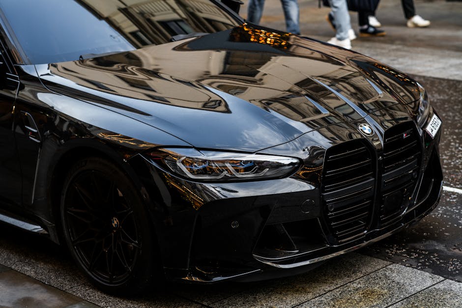 A sleek black BMW M4 parked on a rainy London street, showcasing its luxury design