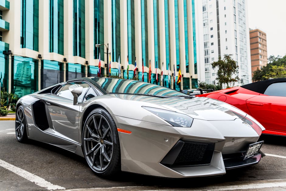 Luxury silver sports car parked in front of modern glass facade building