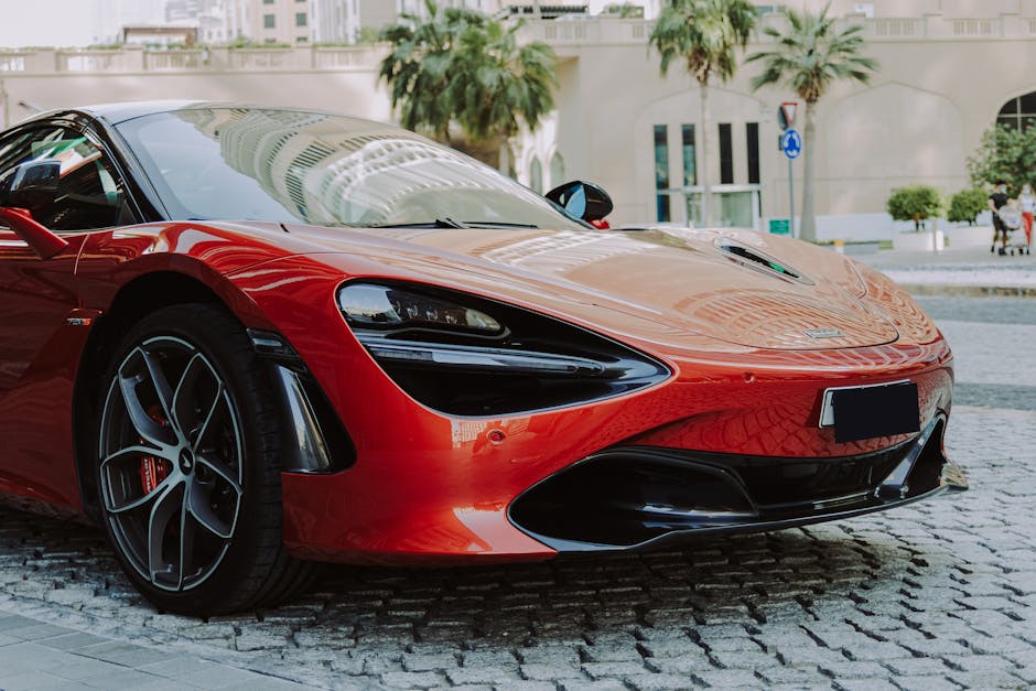 A sleek red luxury sports car parked in downtown Dubai, showcasing modern design and high-end automotive elegance